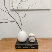 Gem concrete candle burning beside a white vase on a book