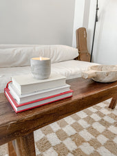 Pebble concrete candle on books on a wood coffee table