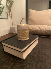 Pillar concrete candle with gilded paint on a book
